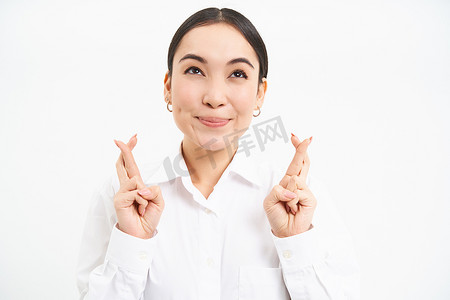 日本女商人交叉手指祈求好运，许愿，寄予厚望，期待某事，站在白色背景中