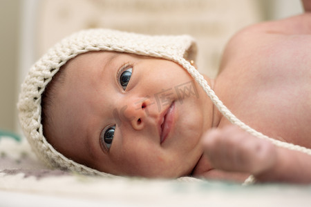 透气摄影照片_两个月大的婴儿在婴儿床里戴着羊毛帽