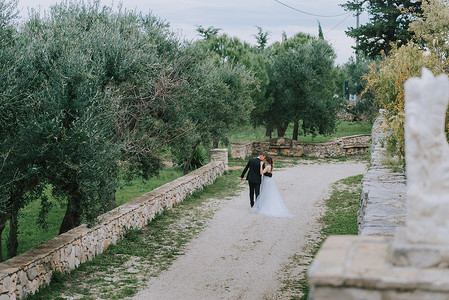 幸福的时尚微笑夫妇在婚礼当天漫步在意大利托斯卡纳。