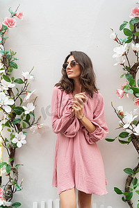 年轻美丽的微笑可爱浪漫的女人穿着时髦的夏季粉红色连衣裙。