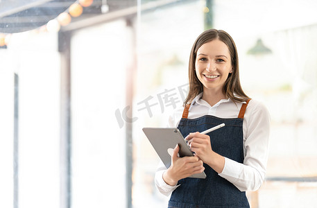 一位笑容灿烂的女人的肖像准备开店欢迎顾客咖啡店的老板正在等待开店，心甘情愿地等待为顾客服务。