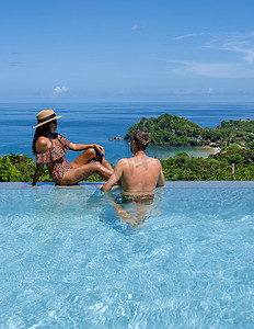 男女喝摄影照片_假期期间，一对年轻男女在游泳池里喝椰子饮料