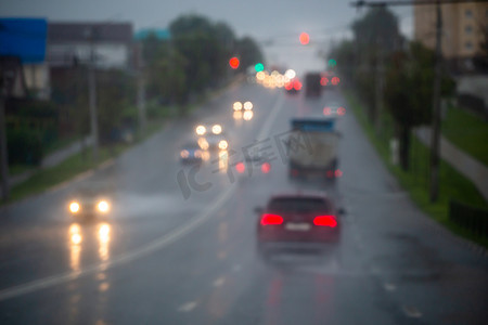 雨后夜间街道汽车交通的离焦图片-从道路上看。