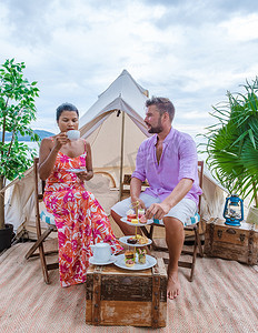 情侣在帐篷前的海滩上喝下午茶，男女在海滩上喝下午茶