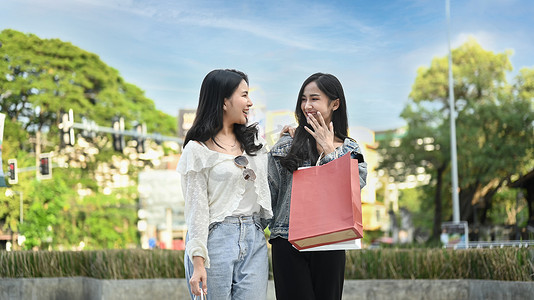 两名年轻的亚洲女性在城市购物区散步时聊天、共度时光的照片