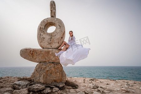 一个女人坐在由大石头制成的石雕上。