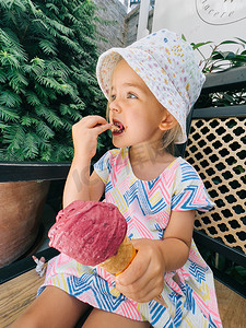 小女孩坐在树旁的长凳上，用抹刀吃冰棒锥