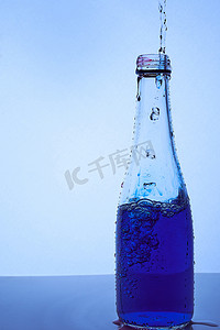 菜单黑金摄影照片_将蓝色液体倒入玻璃瓶中。
