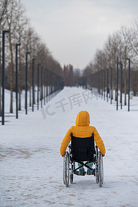 冬天，白人残疾妇女坐在公园的椅子上。