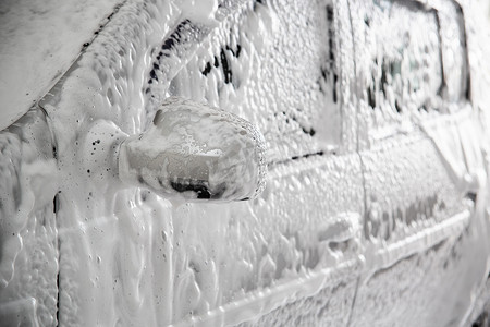 洗车时带有肥皂水固体层的汽车特写视图。