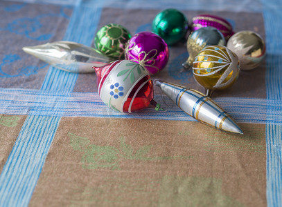 特写旧复古圣诞装饰系列，配有彩色粉色绿色和金色玻璃圣诞小玩意和米色蓝色桌布背景上的冰柱