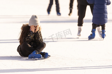 滑冰摔倒摄影照片_人、运动、创伤、疼痛和休闲概念 — 年轻女子在户外溜冰场上摔倒并抱住膝盖