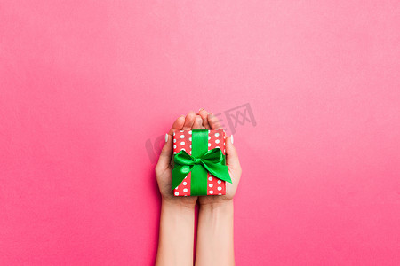包装广告设计摄影照片_女孩手拿着工艺纸礼盒，作为圣诞节或其他节日的礼物，粉红色背景，顶视图有复制空间