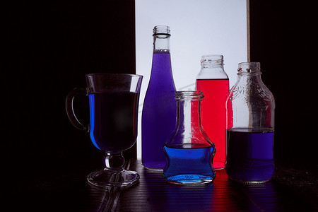 装瓶在浅色背景上，带有蓝色和红色液体剪影照片