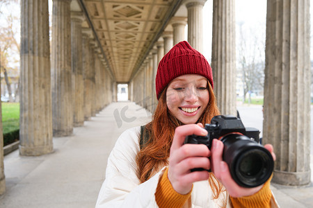 在旅行期间摄影照片_微笑的旅游摄影师，在旅行期间拍照，拿着专业相机并拍照