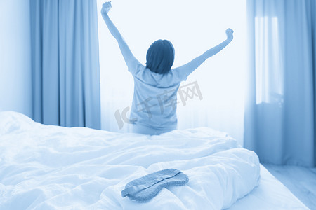 床上戴着睡眠面罩，背景是伸展的女人