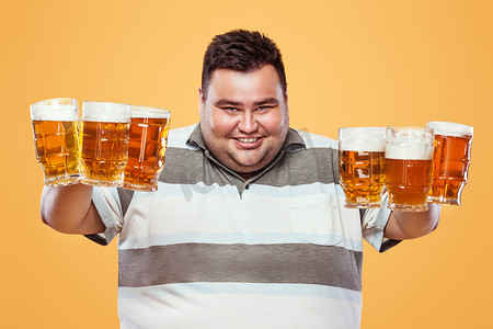慕尼黑啤酒节上的年轻胖子，在黄色背景下喝啤酒。
