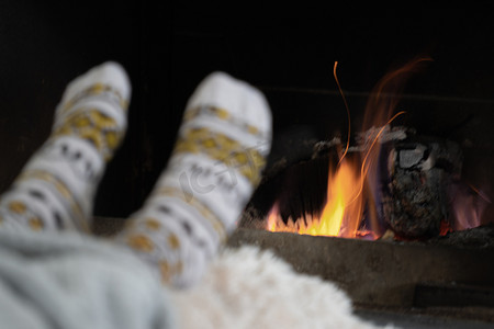 一个冬天的晚上，女孩在乡间别墅燃烧的壁炉旁休息和取暖她的脚。