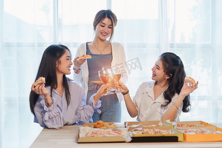 生日聚会上的朋友们用香槟和披萨碰杯，享受圣诞假期，桌上的披萨。