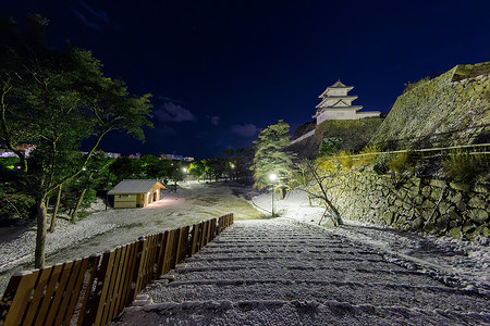 寒冷的冬夜，废弃公园的石墙和城堡塔楼被雪覆盖的楼梯