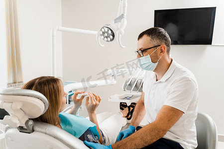 正畸摄影照片_牙医向女性咨询有关使用可拆卸透明牙套矫正器、正畸硅胶训练器的信息。