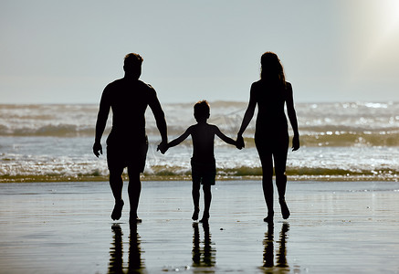 海滩，手牵着手，家人与孩子、母亲和父亲的轮廓在海水中行走，在夏天的天空模型上。