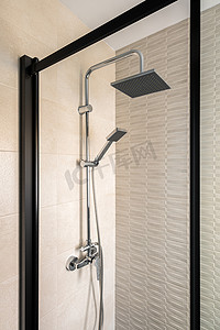 现代瓷砖浴室配有雨头、手持淋浴和带黑色框架的玻璃门。