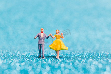 微型人物，在蓝色闪光背景上跳舞的情侣