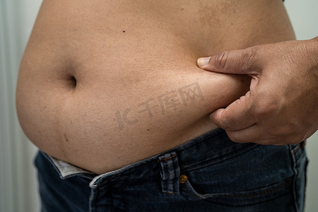 超重的亚洲女性在办公室展示肥胖的腹部。