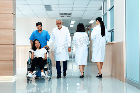 医生和护士在无菌走廊运送坐轮椅的女性患者。