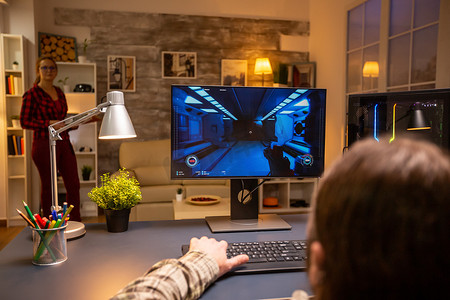 专业视频游戏玩家深夜在客厅在功能强大的电脑上玩游戏的后视图