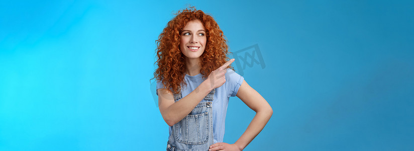 开朗、积极、有魅力、好看、快乐、微笑的红发女郎 25 岁卷发女人夏季工装裤指向左上角看向一边高兴展示促销建议试用
