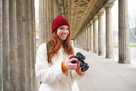 微笑的旅游摄影师，在旅行期间拍照，拿着专业相机并拍照