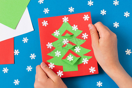 花哨摄影照片_孩子用圣诞树做卡片。