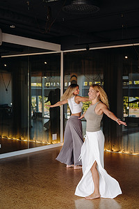 两名穿着运动服的女性正在健身房里做舞蹈瑜伽