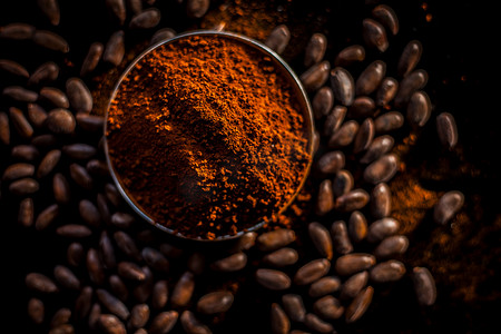 在黑色表面上拍摄生咖啡豆和粉末。