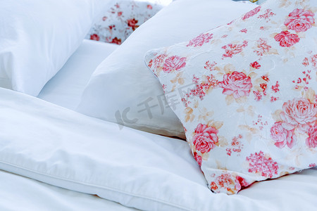 明亮的卧室内饰，床上配有花卉图案枕头
