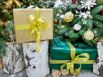房间里圣诞树附近的桦树桩上有一个用金纸包裹着圣诞礼物的漂亮盒子
