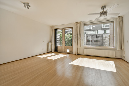 木地板客厅摄影照片_一间空荡荡的客厅，铺着木地板，有一扇窗户