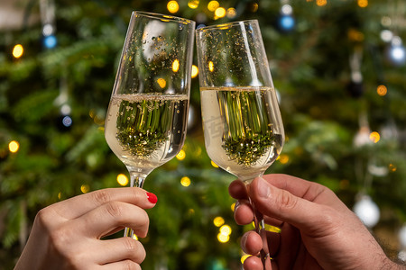 男人和女人在圣诞树下用香槟碰杯