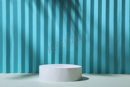 3d蓝色圆柱摄影照片_最小背景蓝色和灰色，带有 3D 圆柱讲台和出生自然阴影，用于在广告中展示产品