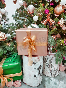 房间里圣诞树附近的桦树桩上有一个用金纸包裹着圣诞礼物的漂亮盒子