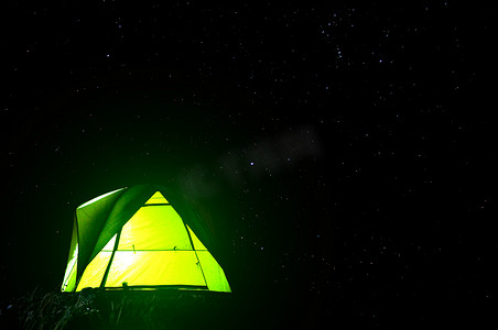 夜间森林和星光背景中露营绿色帐篷