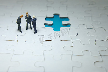 商业策略概念照片 — 三个微型商人讨论上面缺失的拼图