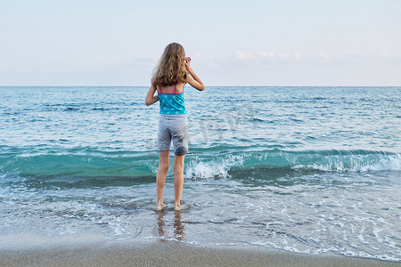 后视图，海滩上的小女孩，看着海平线