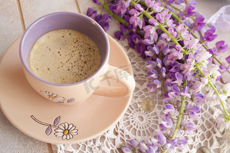 咖啡豆花摄影照片_早晨的场景，一杯咖啡，周围环绕着羽扇豆的紫色野花