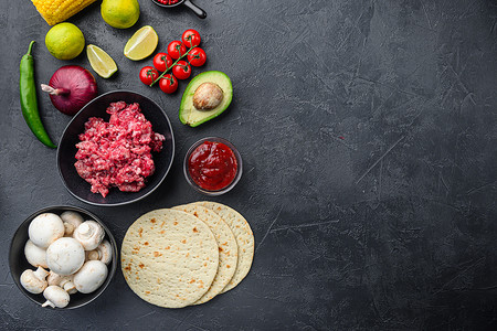 黑色辣椒背景摄影照片_传统的墨西哥玉米饼，混合了配料、玉米、肉类、蔬菜、莎莎酱、黑色纹理背景的酱汁，顶视图带有文字空间。