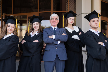 一位教授和他的学生穿着毕业礼服，双臂交叉在胸前站着。