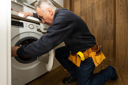 一位老人在修理洗衣机