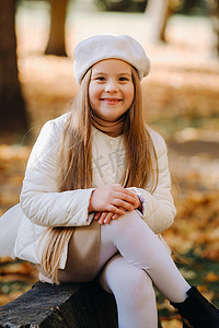 温情情绪摄影照片_一个戴着帽子的快乐女孩在秋季公园散步